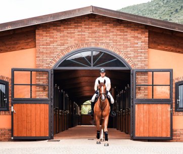 Reiter reitet aus der LO&F Horses Stallgasse nach draußen