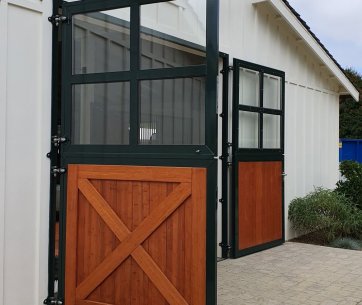 Porte d’écurie ouverte à Milberry Farm avec revêtement en bois élégant et cadre en acier vert