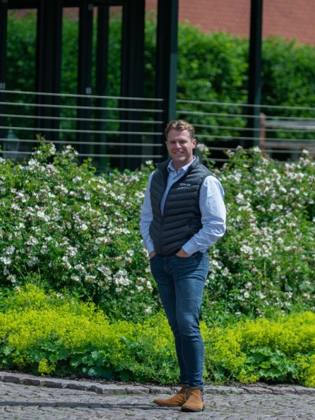 Jeremy LeBlanc steht vor einer Führlange mit einem Blumenbeet davor