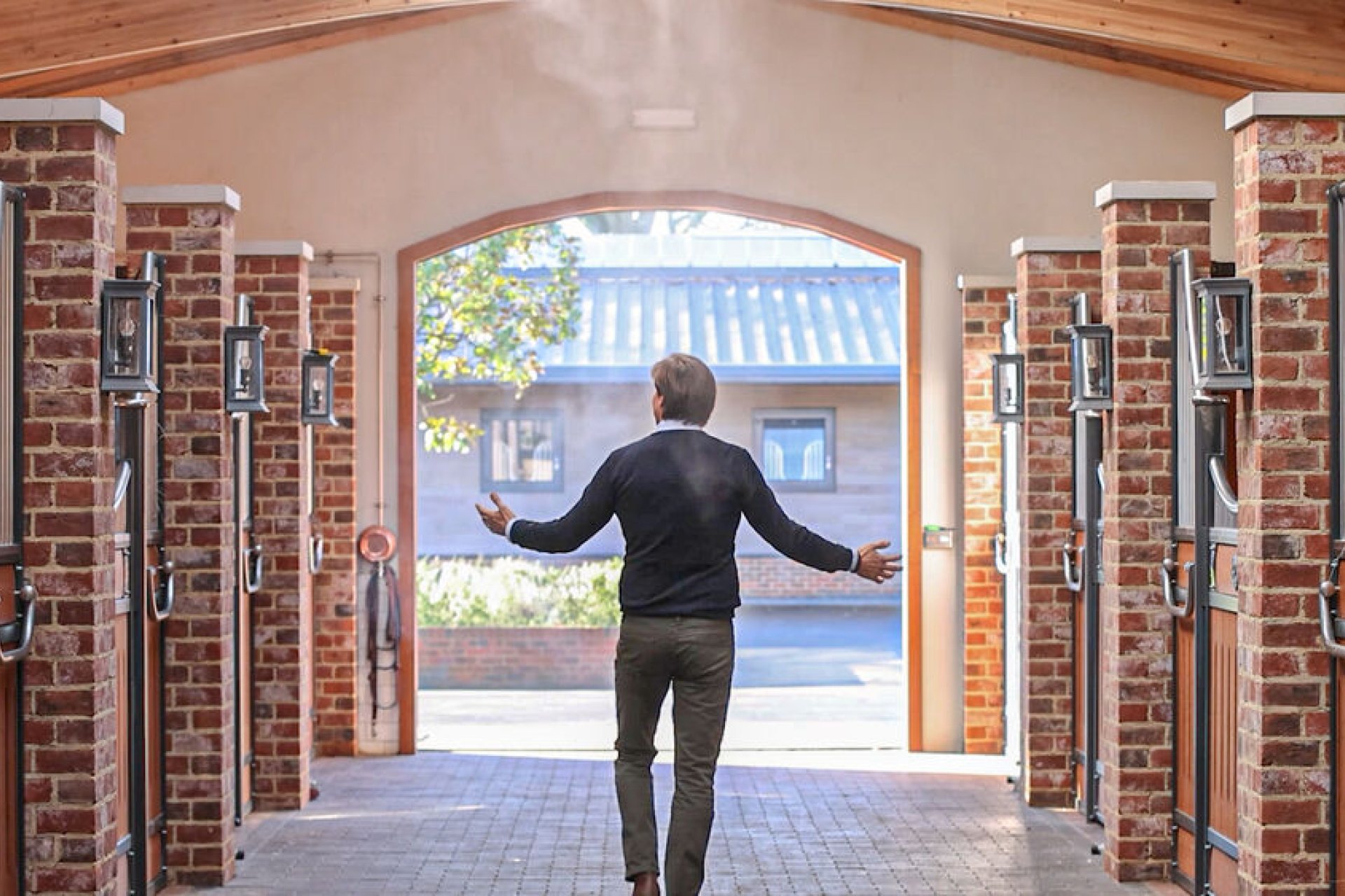 Mensch laeuft durch Stallgasse mit R&AIR Care Vernebelung