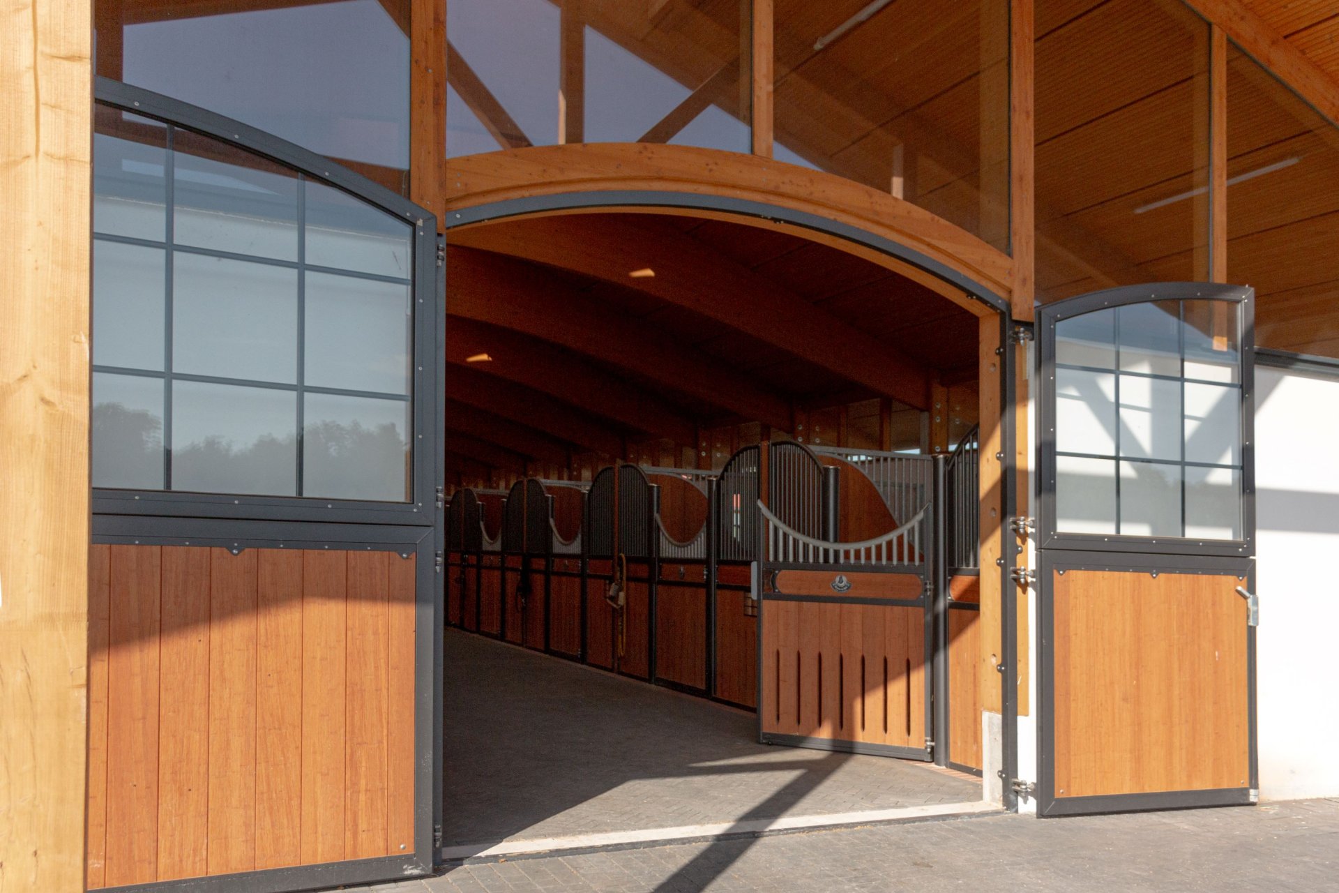 Écurie moderne par Röwer & Rüb avec porte d’entrée ouverte, éléments en acier inoxydable et remplissage en bois de bambou. Conseils d’entretien pour des matériaux durables.