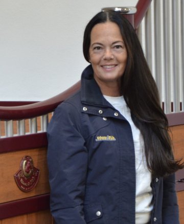 Händlerin steht vor einer roten Pferdebox