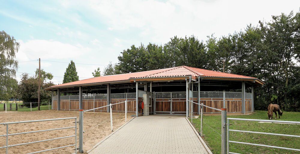 Aussenansicht einer ovalen Fuehranlage mit rotem Dach und Vordach