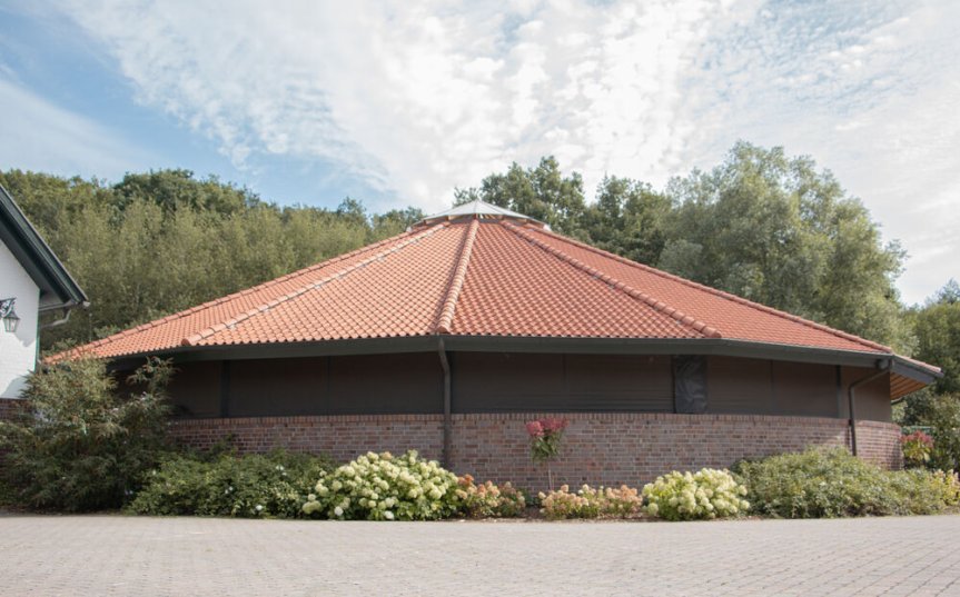 Grosse runde Fuehranlage mit rotem Dach, Windschutznetz und gemauertem Zaun