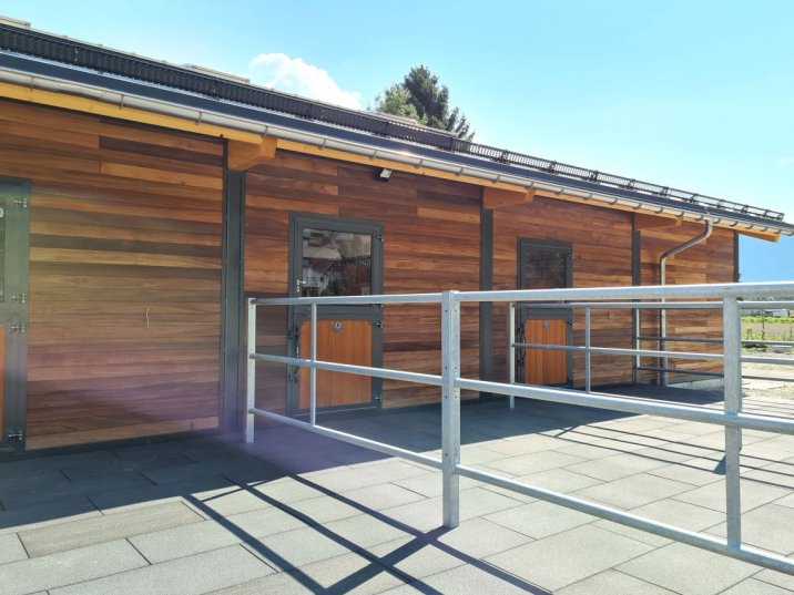 Bâtiment d'écurie avec portes extérieures anthracite et paddock attenant.